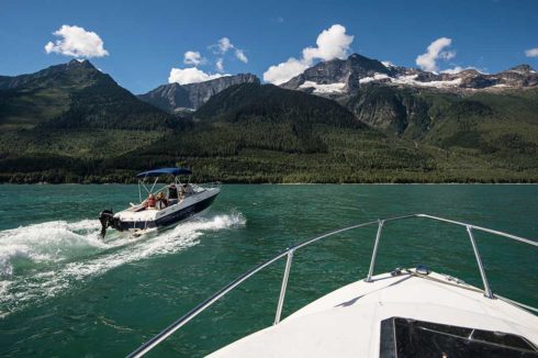 Speedboats on deep green lake with mountain scenery